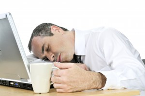 Businessman asleep at his desk on white background