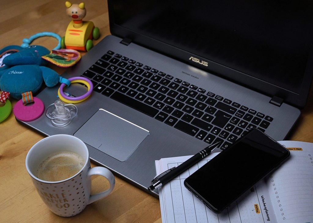 Picture of a laptop with coffee and a children's toy.